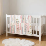 Daisy Dreams baby quilt draped over white crib in neutral nursery with wood floors