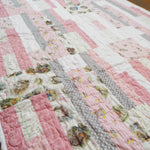 Angled flat lay of Daisy Dreams pink baby quilt