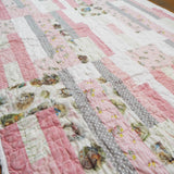 Angled flat lay of Daisy Dreams pink baby quilt