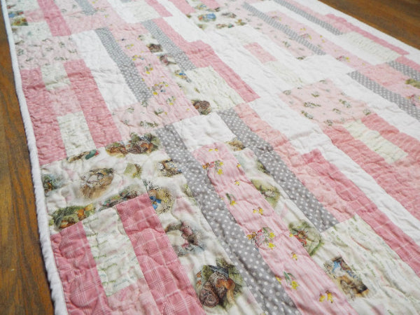 Angled flat lay of Daisy Dreams pink baby quilt