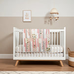Daisy Dreams baby quilt front view draped over a white crib in a neutral nursery