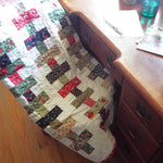 Handmade traditional holiday throw shown folded over a chair that is at a desk