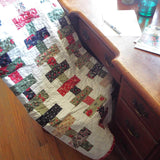 Handmade traditional holiday throw shown folded over a chair that is at a desk