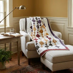 Embers at Dusk lap quilt shown over a chair and ottoman in a reading corner