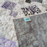 Evening Lattice lap quilt shown with corner flipped up to display backing, tag, and detail stitching