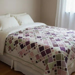 Handmade king quilt in lavender, rose, and sage tones styled in a cozy cottage bedroom with natural light and soft linen bedding.