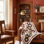 Fireside Links Lap Quilt shown on a tan leather sofa in a traditionally designed living room.