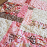 Angled shot of floral hearts handmade quilt showing stitching detail