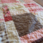 Stylized angled view of handmade floral and heart throw quilt with chocolate back