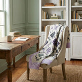 Evening Lattice lap quilt folded over an upholstered chair pulled out from a wooden deks