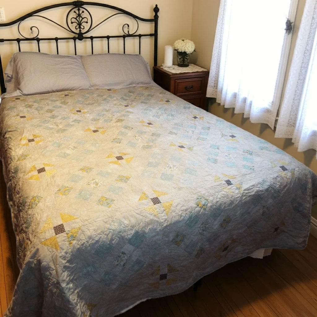 Handmade queen quilt in soft honey and aqua floral tones styled in a minimal farmhouse bedroom