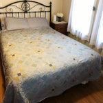 Handmade queen quilt in soft honey and aqua floral tones styled in a minimal farmhouse bedroom