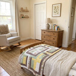 Honeyed Tails Baby Quilt shown folded on a child's bed.
