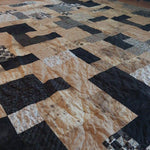 Angled lay of Inkstone King quilt showing fabrics and stitching detail.