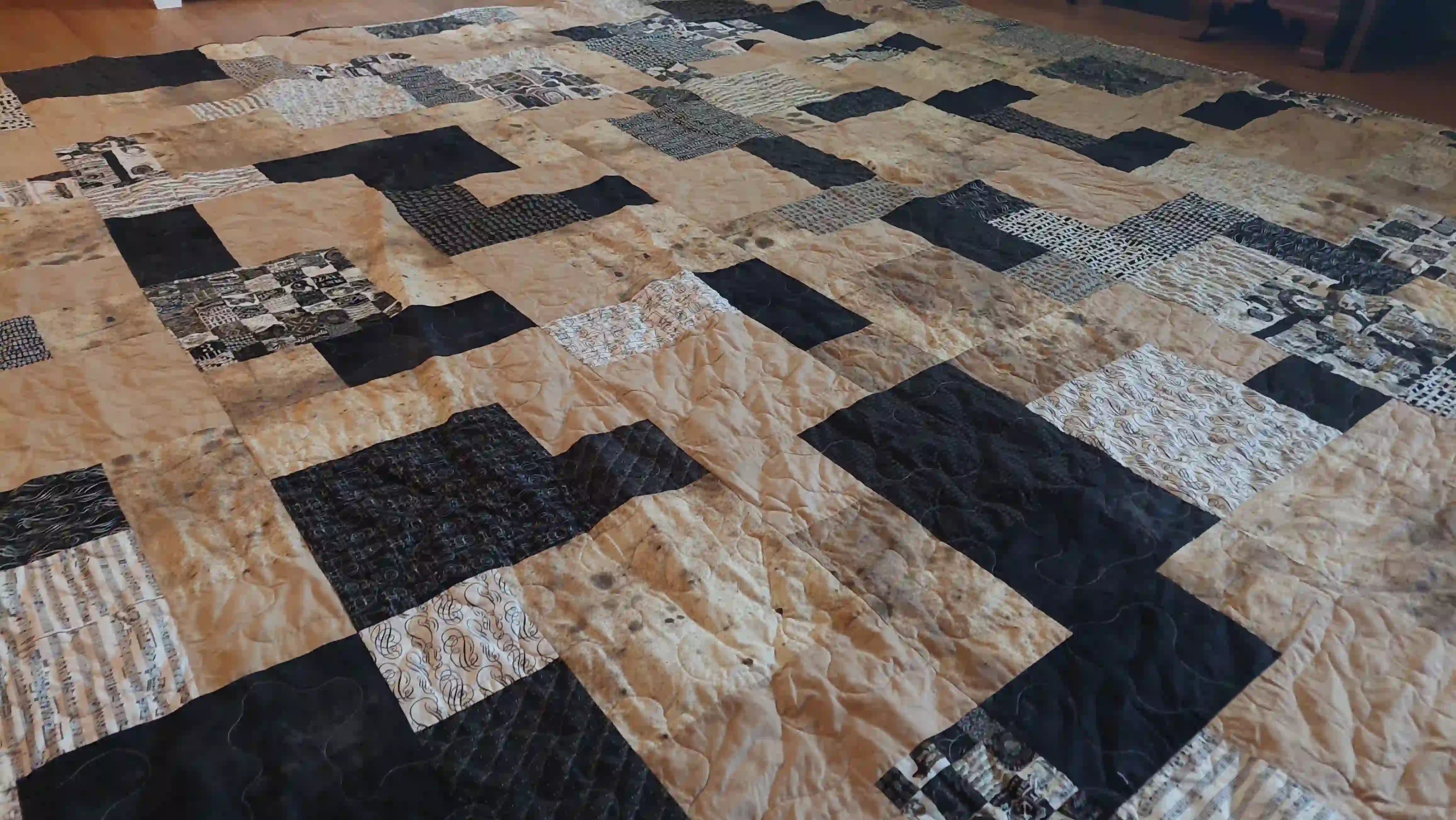 Angled lay of Inkstone King quilt showing fabrics and stitching detail.