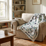 Links to the Past Lap Quilt shown draped on an oversized upholstered chair in a neutrally decorated reading nook.