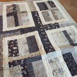 Angled lay of Little Framework Baby Quilt showing closer look at fabrics.