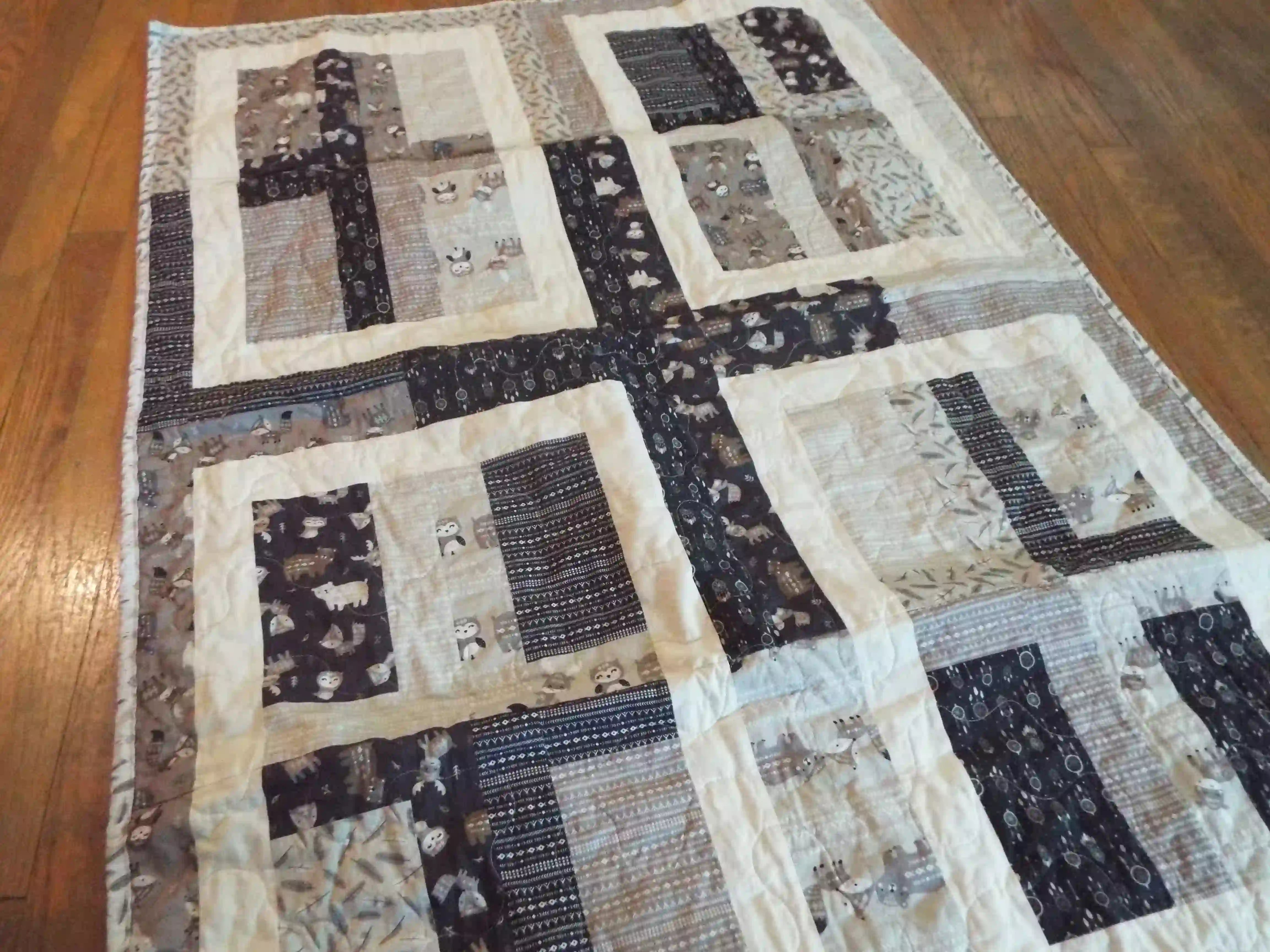 Angled lay of Little Framework Baby Quilt showing closer look at fabrics.