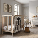 Little Framework Baby Quilt shown draped over a crib in a pale gray nursery.