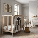 Little Framework Baby Quilt shown draped over a crib in a pale gray nursery.