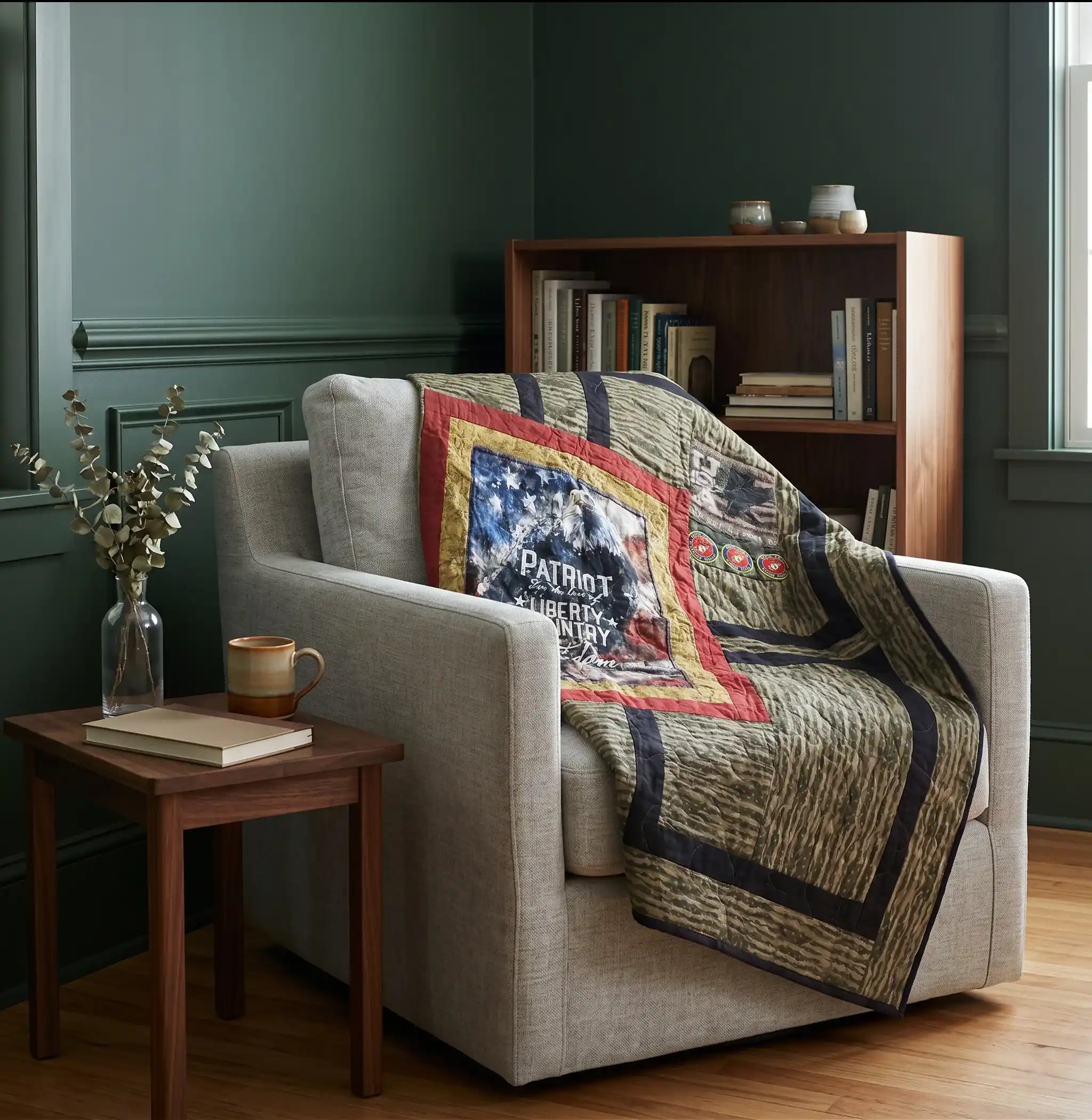 A living room scene with a light beige armchair draped with Marine Eagle Handmade Throw Quilt. A small wooden side table with a vase and book sits beside the chair, and a wooden bookcase is in the background against dark green walls.
