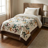 Quilt shown on a twin bed in a simply decorated room