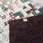 Quilt shown with corner flipped over to show backing and stitching detail