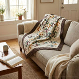 Quilt shown draped over a neutral couch in a living room