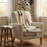 Elegant holiday quilt draped over the back of an armchair with a Christmas tree in the background