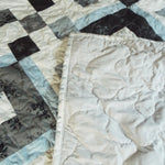 Corner flipped of modern black and white handmade quilt showing backing and stitching detail