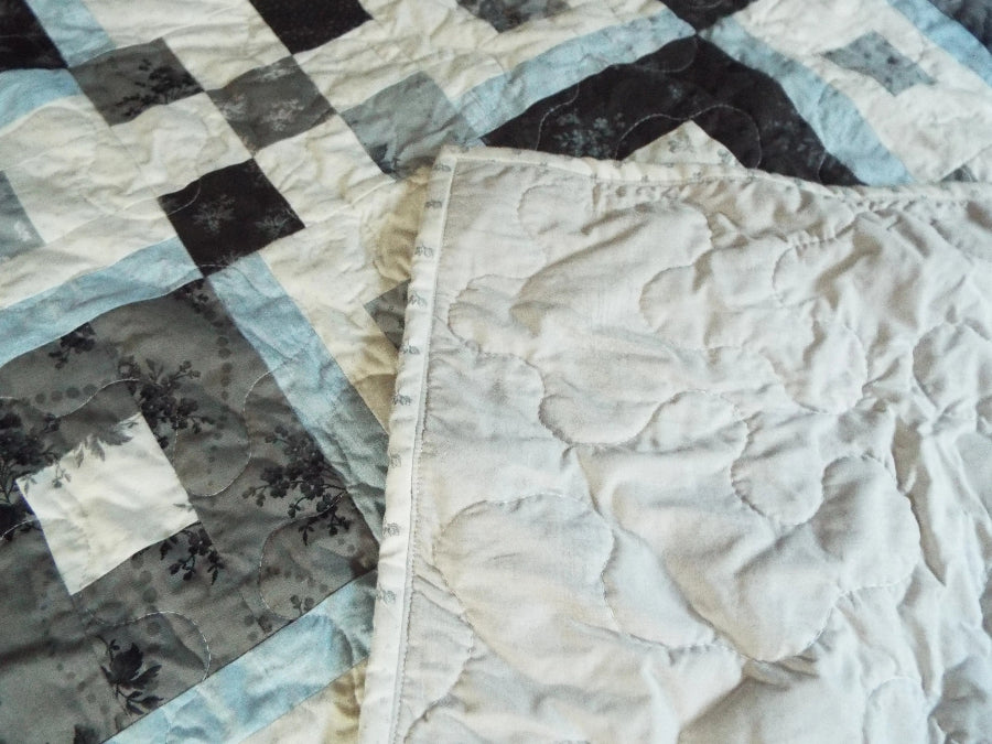 Corner flipped of modern black and white handmade quilt showing backing and stitching detail