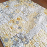 Angled lay of quilt showing stitching detail and close up of fabrics