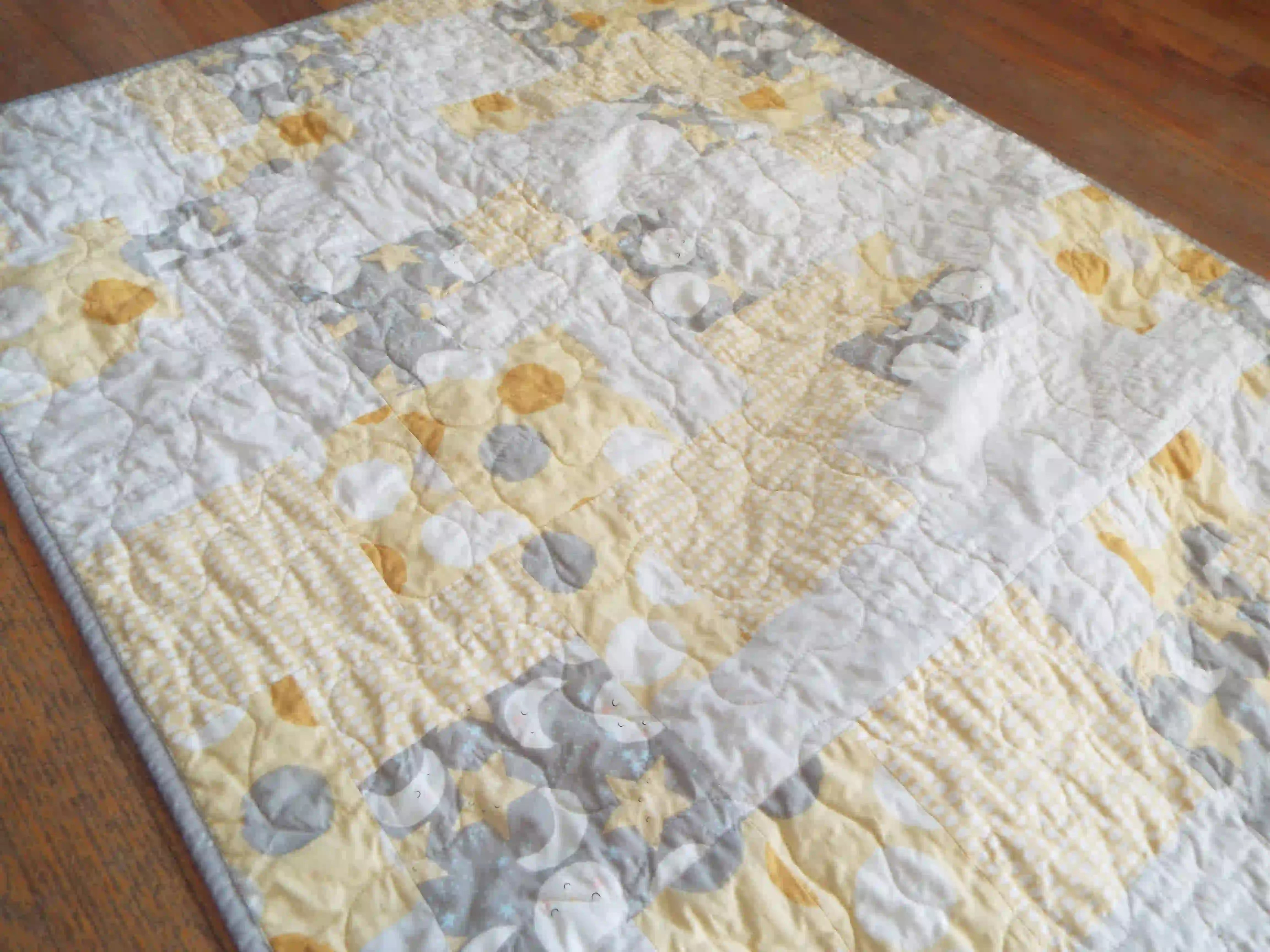 Angled lay of quilt showing stitching detail and close up of fabrics