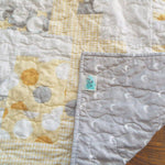 Quilt shown with corner flipped over to show backing fabric and stitching detail