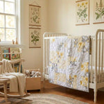 Quilt shown draped over a crib in a creamy yellow nursery