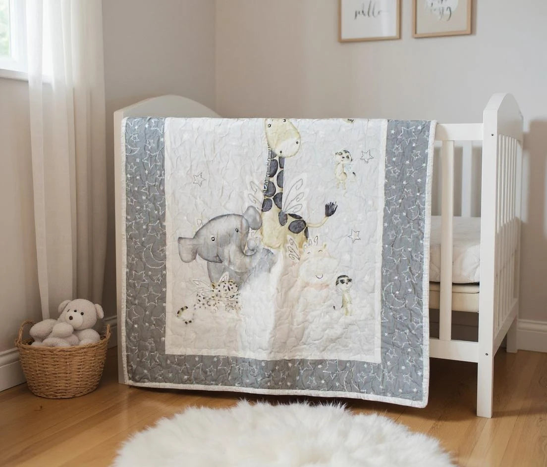 Handmade gray and white safari animal baby quilt hanging on white crib in softly lit nursery