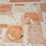 Close-up of the quilt’s center blocks showing detailed hare illustrations, soft peach tones, and gentle meandering quilting stitches.