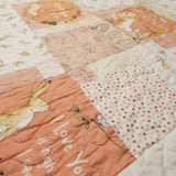 Angled detail shot of the baby quilt’s patchwork sections, showing fabric textures, soft color transitions, and the delicate quilting pattern.