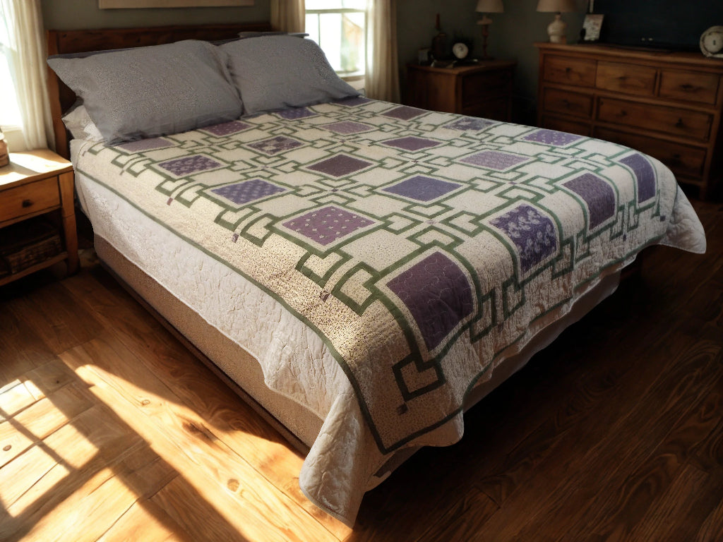 Handmade purple throw quilt spread across a queen-size bed in a cozy sunlit bedroom with wooden furniture and soft lighting.