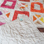 Handmade lap quilt showing the corner flipped up to see backing, binding, and quilt top.