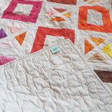 Handmade lap quilt showing the corner flipped up to see backing, binding, and quilt top.