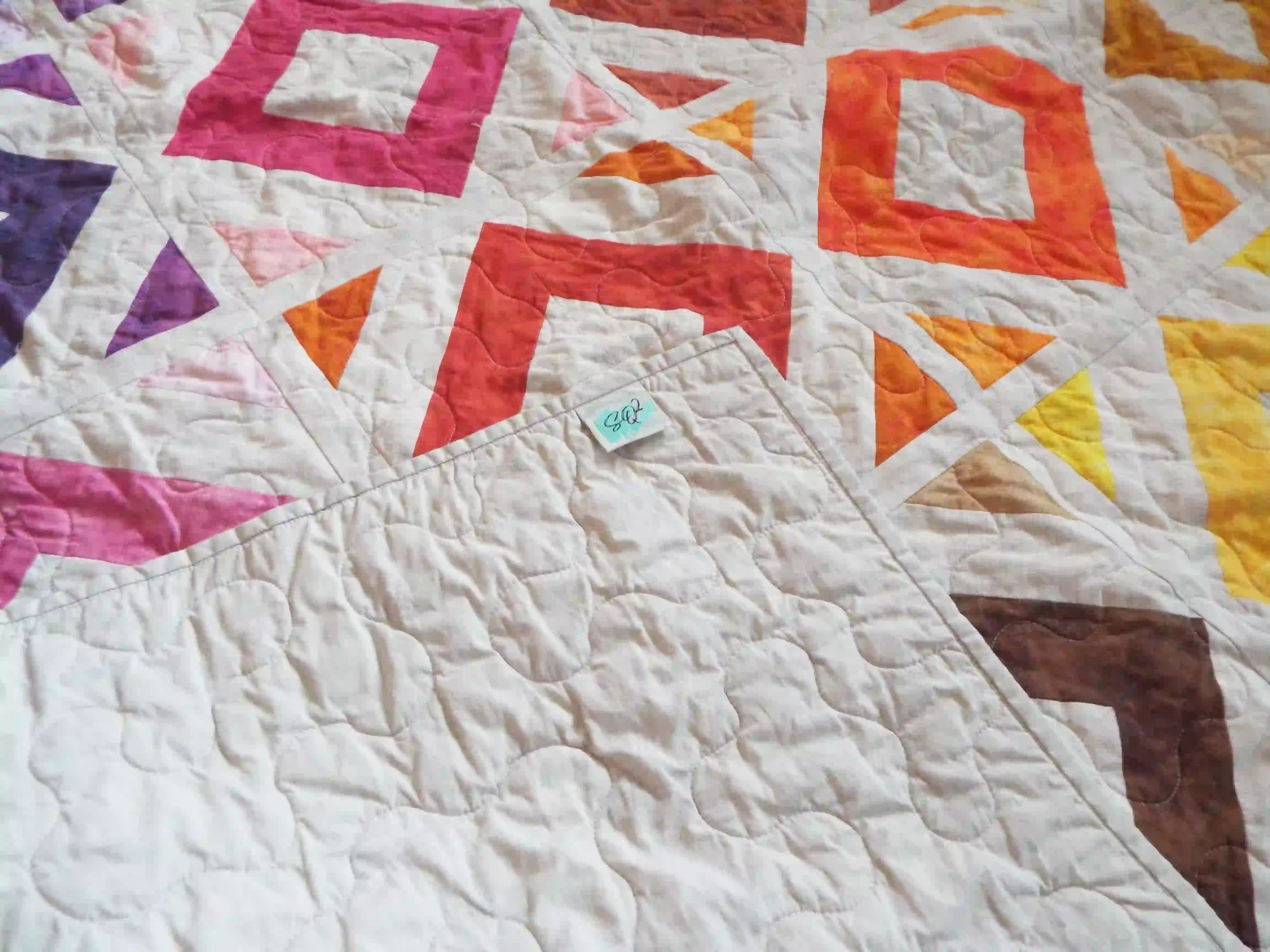 Handmade lap quilt showing the corner flipped up to see backing, binding, and quilt top.