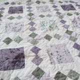 Angled lay of Quiet Meadow showing prints from the quilt