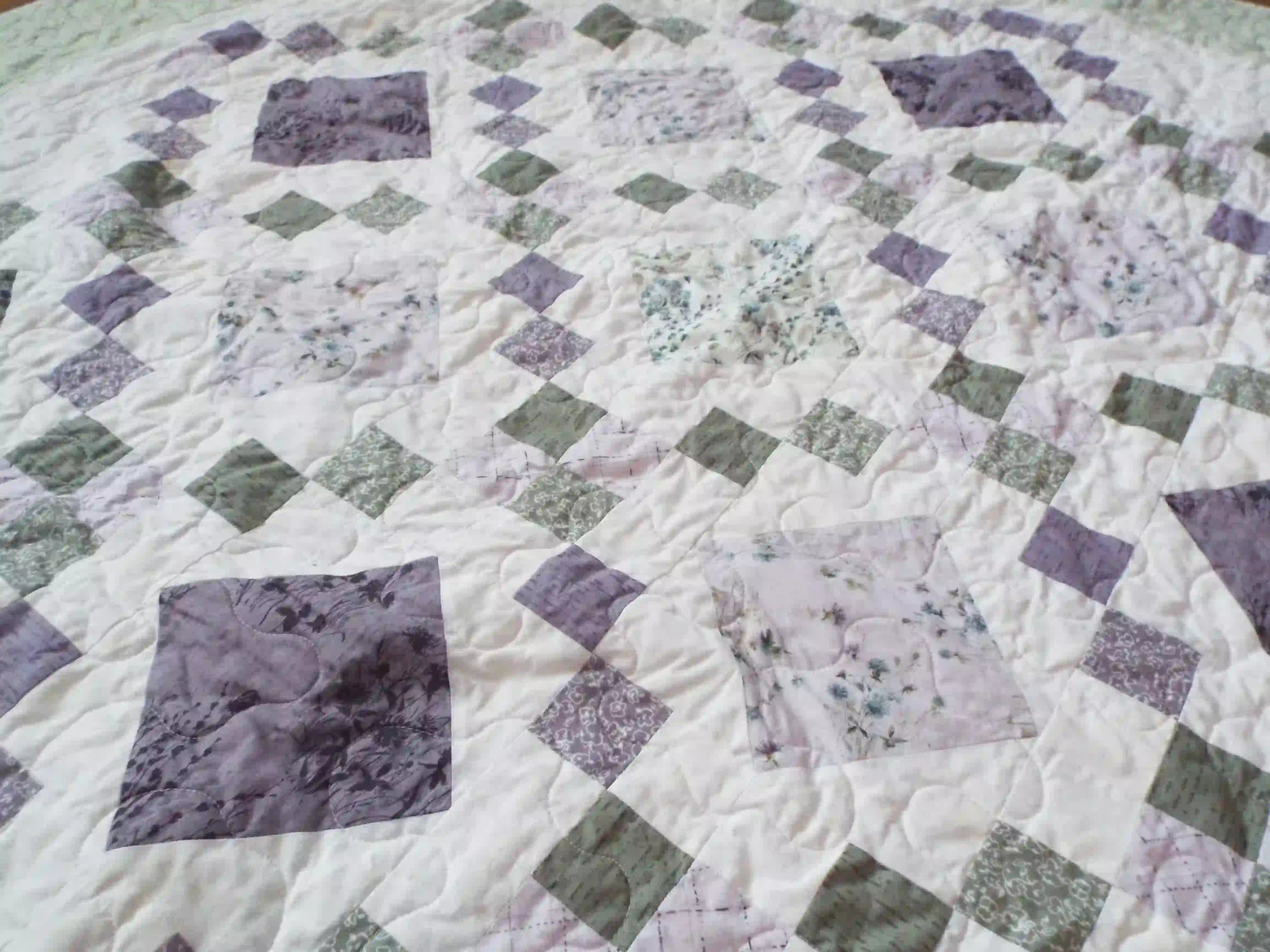 Angled lay of Quiet Meadow showing prints from the quilt