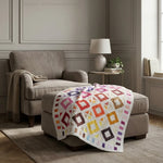 Handmade lap quilt shown on an ottoman in a gray living room