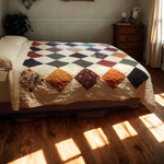 Close-up of handmade patchwork quilt featuring gold, plum, and forest green floral prints.