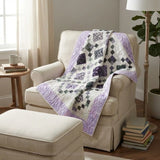 Evening Lattice lap quilt shown on an upholstered chair with ottoman in neutrally decorated room