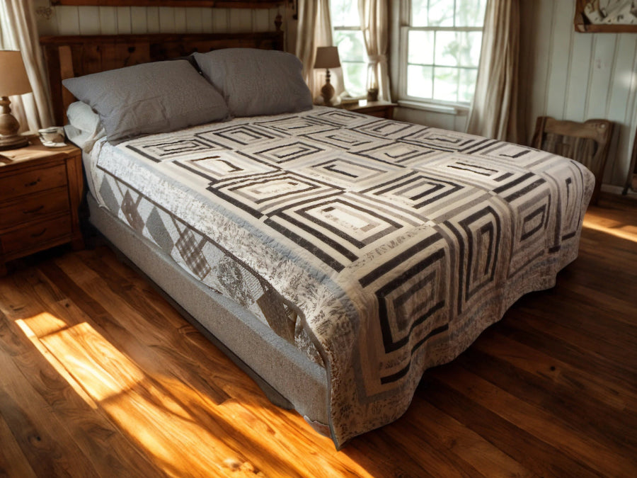 Handmade black and white quilt with rectangular blocks styled on a wooden bed in a cozy farmhouse-inspired bedroom