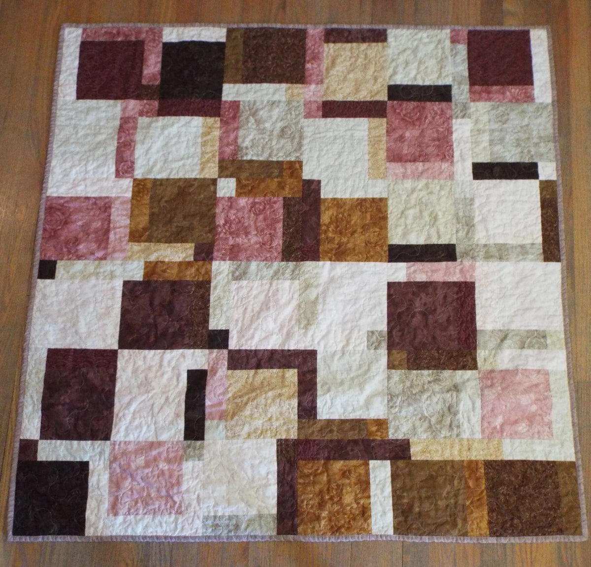 Flat lay of handmade quilt done in shades of brown, rose, and cream