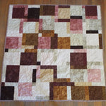 Flat lay of handmade quilt done in shades of brown, rose, and cream